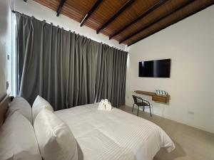 a bedroom with a white bed and a television at Vida Playa El Agua in La Mira