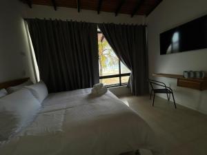 a bedroom with a large white bed and a window at Vida Playa El Agua in La Mira