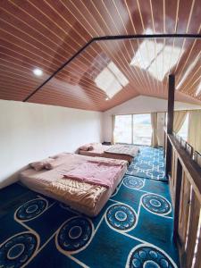 two beds in a room with a wooden ceiling at Lavenda homestay syari'ah in Dieng