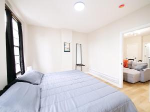 a white bedroom with a large bed and a couch at Cozy 1BR Getaway with Wifi - Mins to NYC in Paterson