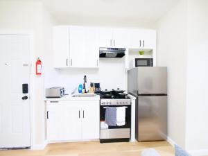 a kitchen with white cabinets and a stainless steel refrigerator at Cozy 1BR Getaway with Wifi - Mins to NYC in Paterson