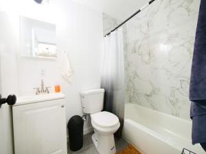 a white bathroom with a toilet and a shower at Cozy 1BR Getaway with Wifi - Mins to NYC in Paterson