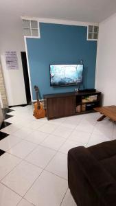 a living room with a guitar and a flat screen tv at Casa Azul Jaraguá in São Sebastião