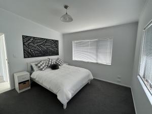 a white bedroom with a bed and a window at The Shores Lakefront Retreat in Omamari