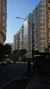 a person walking down a city street with tall buildings at A uma quadra da praia de Copacabana in Rio de Janeiro