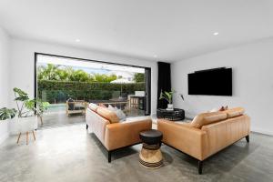 Nalu Beach House - Kingscliff Getaway by uHoliday في كينغسكليف: غرفة معيشة مع أريكتين وتلفزيون بشاشة مسطحة