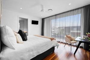 Nalu Beach House - Kingscliff Getaway by uHoliday في كينغسكليف: غرفة نوم بها سرير ونافذة كبيرة +20 صورة
