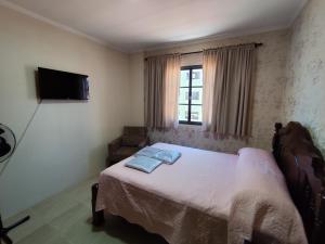 a bedroom with a bed and a tv on the wall at Apartamento aconchegante no centro da cidade in Serra Negra