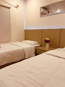 ClorindaにあるSHINY Houseのベッド2台 ホテルルーム 花のテーブル付
