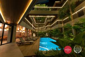 an indoor pool in a building with chairs and plants at Piece Lio from Japan Managed by H Hospitality Group in El Nido