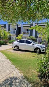 une voiture blanche garée devant une maison dans l'établissement MSFlats Paripueira Praia Wifi Ar Cozinha e Varanda Nascente c Rede, à Paripueira