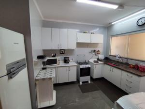 a small kitchen with white cabinets and a microwave at Apartamento aconchegante no centro da cidade in Serra Negra +19 photos