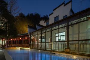 een gebouw met een zwembad in de nacht bij 花筑庐江满山红遍民宿 