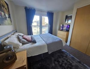ein Schlafzimmer mit einem Bett und einem Fenster mit blauen Vorhängen in der Unterkunft Cardiff City Apartment near Principality Stadium, Cardiff Arms Park & Cardiff Castle in Cardiff