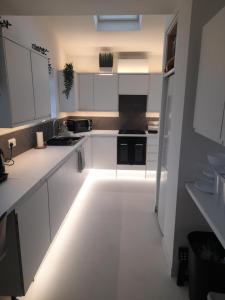 ディドコットにあるGreenviewの白いキャビネットと床の照明が付いたキッチン