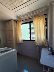 a bathroom with a window and a washing machine at Apartamento aconchegante no centro da cidade in Serra Negra