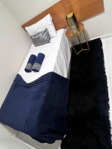 a bed with two blue slippers on top of it at Apartamento em Frente ao Shopping Itaguaçu in São José