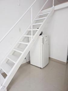 a white staircase next to a refrigerator in a room at Apartaestudio - Miraflores in Cali