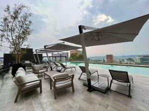 a patio with chairs and umbrellas and a pool at Luxury stay in zone 14 in Estación Pamplona