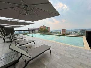 una piscina con bancos y sombrillas en un edificio en Luxury stay in zone 14, en Estación Pamplona