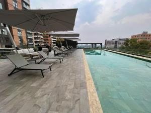 Una piscina con sillas y una sombrilla en un edificio. en Luxury stay in zone 14, en Estación Pamplona 39 fotos más