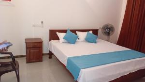 a bedroom with a bed with blue pillows and a fan at Ariyana Sky Suites in Matara