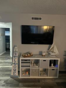 een wit entertainmentcentrum met een flatscreen-tv aan de muur bij Magical Mermaid Condo in New Smyrna Beach