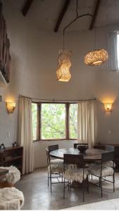 une salle à manger avec une table, des chaises et des fenêtres dans l'établissement Cabañas Bendita Tierra - Calandrias, à Los Molles