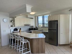 Una cocina con gabinetes blancos y un refrigerador negro. en Seascape Serenity in Palm Beach, en Gold Coast