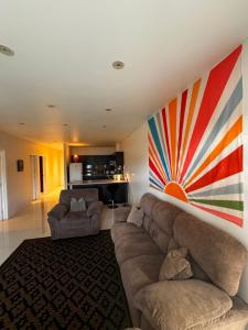 a living room with a couch and a painting on the wall at Bula Bliss Nadi - 2 Bedroom Apartment with Sunset View in Nadi