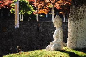 een stenen standbeeld naast een boom bij SSAW Garden Hotel Ningbo Xikou in Fenghua