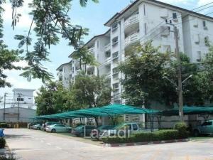 ein Gebäude mit grünen Sonnenschirmen vor einem Parkplatz in der Unterkunft Great Value Residence in Bangna