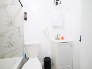 a white bathroom with a toilet and a sink at Comfy 1-Bedroom Escape Close to NYC with Wifi in Paterson +1 photo