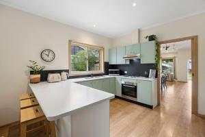 una cucina con armadi verdi e piano di lavoro bianco di Riviera Retreat, Coastal Comfort Near Jan Juc Surf Beach a Bellbrae
