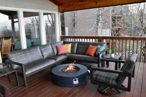 a screened porch with a couch and a fire pit at Paws at the Peak in Beech Mountain