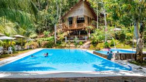een resortzwembad met een boomhut op de achtergrond bij Fundo Baños in Tarapoto