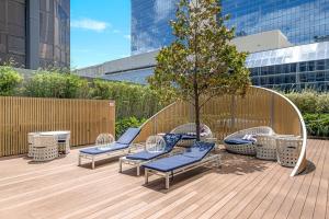 een terras met stoelen en een boom op een gebouw bij Stylish 2BR Next to Parramatta Station with Pool in Sydney
