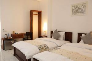 a room with three beds and a desk in it at My Luang Prabang Guesthouse in Luang Prabang