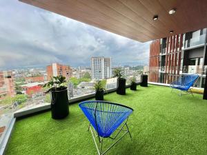 un balcon sur le toit avec des chaises bleues et de la pelouse verte dans l'établissement Urban Corner in Zone 4, à Guatemala