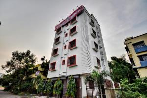 a white building with red windows and a fence at Hotel O Om Shanti International in Jādabpur +18 photos