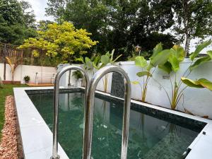 a swimming pool with metal faucets in a backyard at Nisha Grean Heaven in Weligama