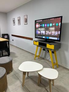 a tv on a stand with a table with a stool at Orillas del Sol Triplex in Chascomús