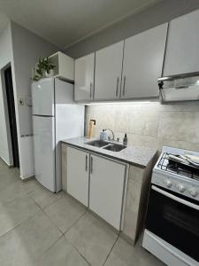 a kitchen with white cabinets and a sink and a stove at Orillas del Sol Triplex in Chascomús