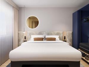 een slaapkamer met een groot wit bed en een spiegel bij Mercure Hotel Den Haag Central in Den Haag +53 foto's