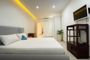 ein Schlafzimmer mit einem weißen Bett und einem TV an der Wand in der Unterkunft Modern 2 Bedroom Apartment Next to the Promenade R2 in Gżira