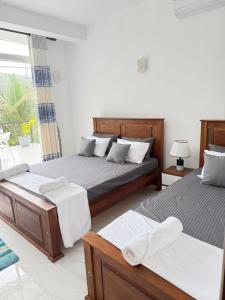 a bedroom with two beds and a balcony at Kandy Villa Grey in Talatuoya