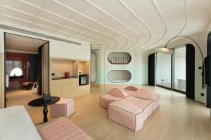 Una sala de estar con muebles rosas y una cocina. en Vignette Collection Tiancheng Belmont Hotel Sanya by IHG, en Sanya