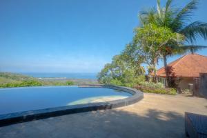 a swimming pool next to a house with a palm tree at Maria Secret Villa in Lovina