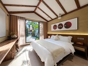 een slaapkamer met een groot bed en een groot raam bij Chengdu Xiaoya Yard Hot Spring Hotel,Enjoy Soaking in natural hot springs,Traditional Chinese afternoon tea,Exquisite fruit platter in Longqiao +160 foto's
