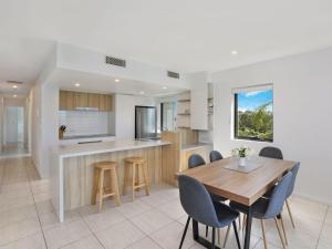 een keuken en eetkamer met een houten tafel en stoelen bij Foreshore Bradman in Diddillibah